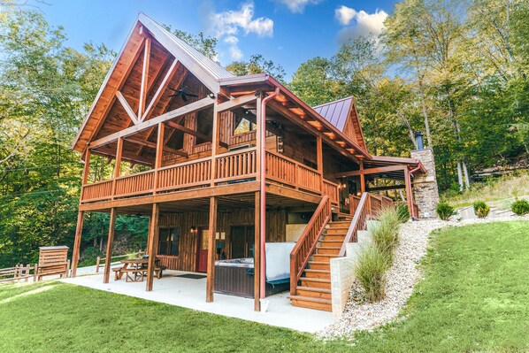 A wooden cabin with a deck, outdoor seating, and a hot tub.