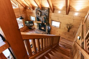 A wooden interior with a fireplace, wooden beams, and a staircase.
