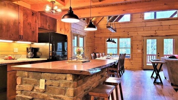 L’intérieur d ’une cabane en bois comprend un îlot de cuisine, un plan de travail en pierre et un coin repas.