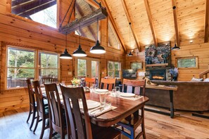 L'intérieur d'un chalet en bois comprend un coin repas, une cuisine et une cheminée.