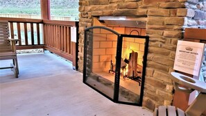 A stone fireplace with a fire, a wooden bench, and a sign on the wall.