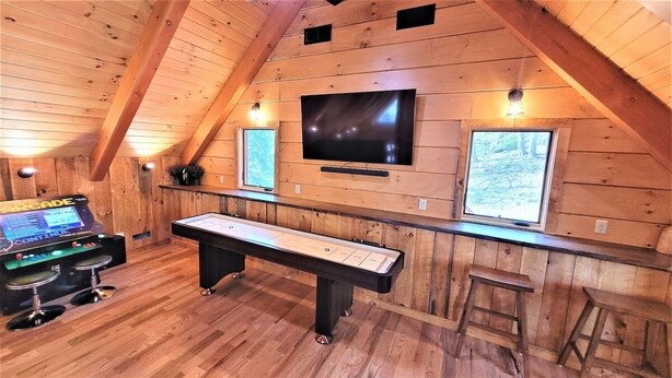 A wooden interior with a pool table, bar stools, and a mounted TV. - Rock Hollow Cabin - Built For Quality! (Rockbridge)