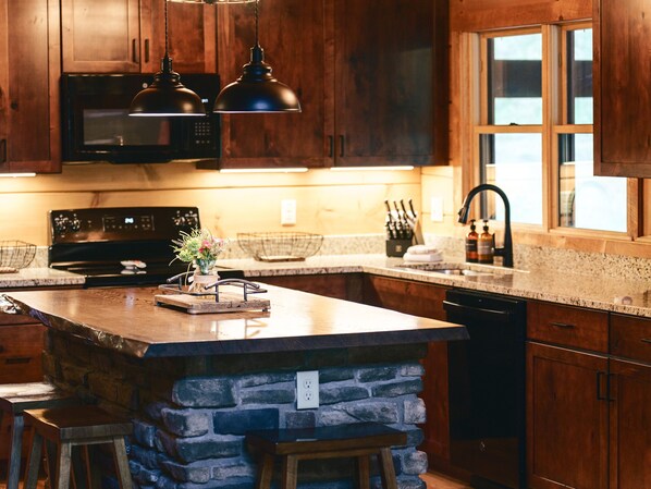 A kitchen with wooden cabinets, a granite countertop, a built-in stove, and pendant lighting.