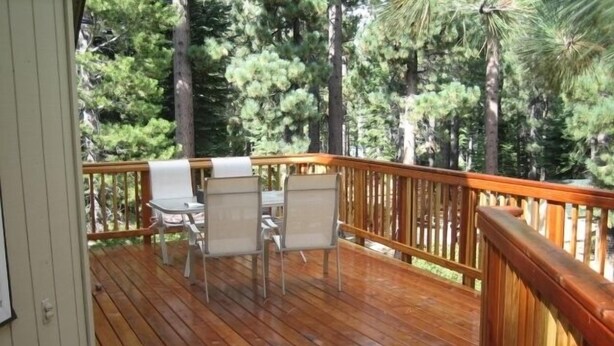 A wooden deck with a table and chairs, surrounded by a wooden railing. - Comfortable, Spacious, Pet-Friendly Home
Located close to all the best of Tahoe (South Lake Tahoe)