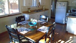 A dining area with a wooden table, four chairs, and a bowl. There are cabinets, a refrigerator, and a microwave in the kitchen area. - Comfortable, Spacious, Pet-Friendly Home
Located close to all the best of Tahoe (South Lake Tahoe)