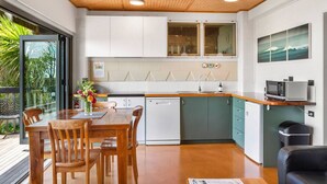 A modern kitchen with white cabinets, a wooden countertop, and a dining area with wooden chairs. - G SPOT lower level WITH SPA (Raglan)