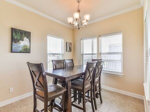 A dining area with a rectangular table, six chairs, and a chandelier. - Sea Turtle Tango- Close to beach! Community Pool! (Galveston)