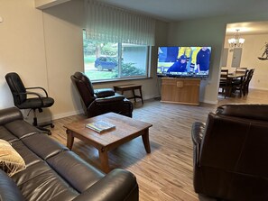 A living room with a leather sofa, a wooden coffee table, and a television displaying a sports event.