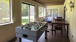 Ein Zimmer mit Tischkicker, Esstisch und einer Couch.