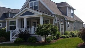 A two-story house with a front porch, a covered entryway, and a well-maintained lawn. - Bay Point Experience (Marblehead)