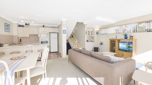 Un appartement moderne comprenant une cuisine, un coin repas, un salon et un escalier menant à l’étage supérieur.