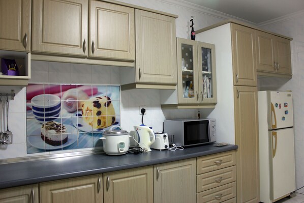 A kitchen with light wooden cabinets, a microwave, a toaster, and a kettle on the counter.