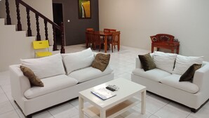 Ein modernes Wohnzimmer mit zwei weißen Sofas, einem Couchtisch und einem Essbereich mit Holztisch und -stühlen.