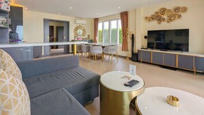 Een moderne woonkamer met een grijze bank, een ronde salontafel en een flatscreen-televisie.