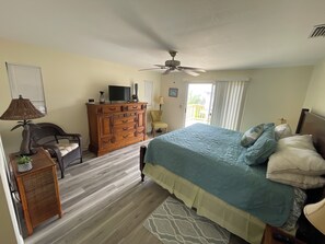 Un dormitorio con cama, cómoda, silla y ventilador de techo.