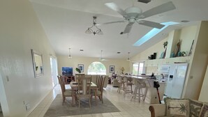 A spacious living area with a dining table, sofas, and a kitchen in the background.