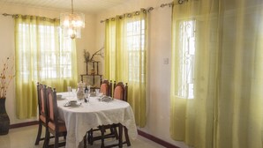 A dining room with a round table set for six, surrounded by wooden chairs. - Comfortable beachfront cottage, full amenities, fabulous deck overlooking beach  (St. Peter)