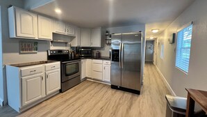 Une cuisine moderne avec des meubles blancs, des appareils en acier inoxydable et un plancher en bois.