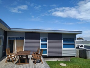 A modern house with a patio, a table, and chairs. - Relax in Rangiputa - Decks, Beaches and Boating (Rangiputa Beach)