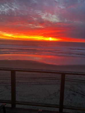 A sunset over the ocean with a wooden deck in the foreground.