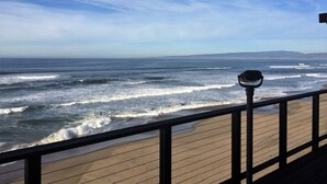 A wooden deck with a telescope, overlooking the ocean waves.