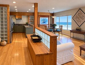 A spacious kitchen with wooden cabinets, a stainless steel refrigerator, and a dining area with a view of the ocean. - Beach Front Vacation Rental-The Beach is your back yard - Santa Cruz (Watsonville)