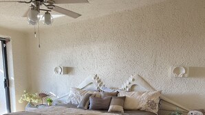 A bedroom with a bed, a nightstand, a ceiling fan, and a textured wall. - Terrasol 2BR/2BA Beach Condo - Best Price, Best Location & Ocean beachfront (Cabo San Lucas)