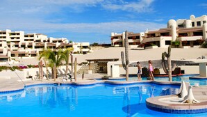A resort pool area with multiple pools, palm trees, and a building with balconies. - Terrasol 2BR/2BA Beach Condo - Best Price, Best Location & Ocean beachfront (Cabo San Lucas)
