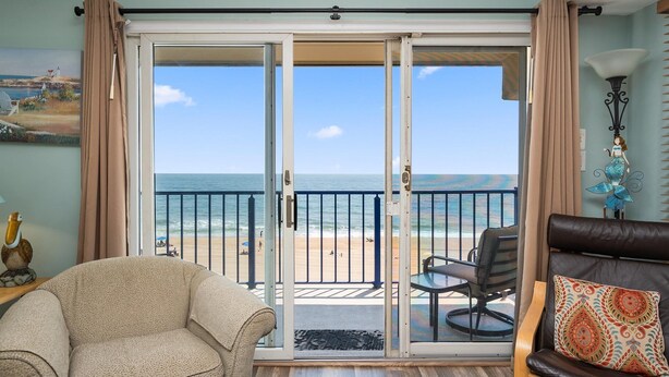 A living room with a view of the beach through a sliding glass door.