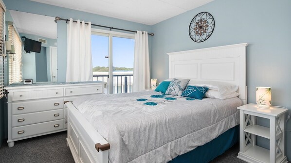 A bedroom with a bed, a dresser, a nightstand, a mirror, and a view of the outdoors. - 🏖️Cozy 2 Bedroom Ocean Front Unit right on the beach, North OC🏖️ (Ocean City)