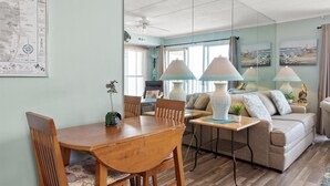 A cozy living room with a wooden dining table, a sofa, and two lamps.