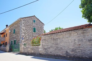 A stone building with a tiled roof, a green gate, and a flower box.