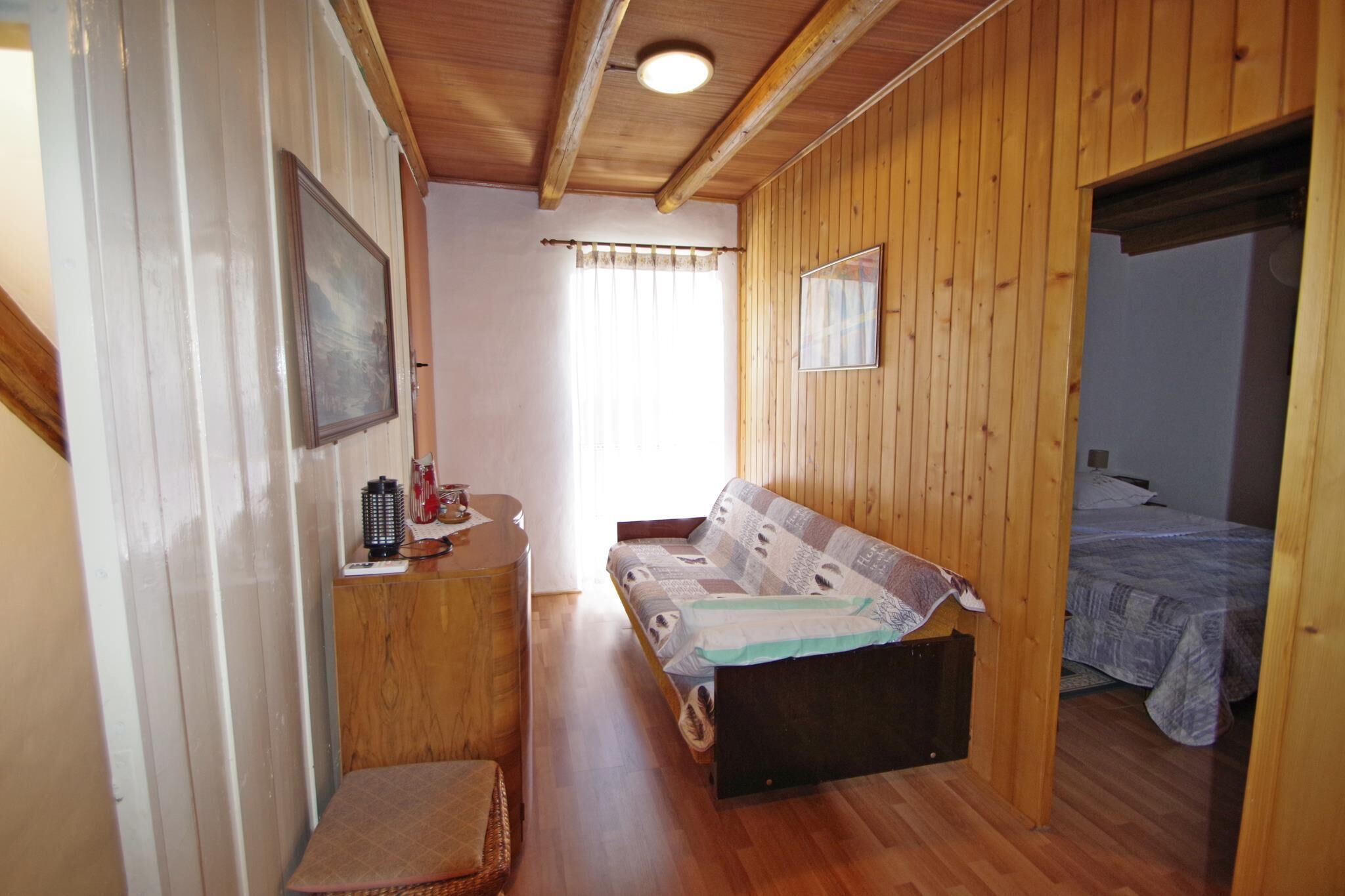 Une pièce chaleureuse avec un banc en bois, une petite table avec une bouilloire et un lit recouvert d’une courtepointe à motifs.