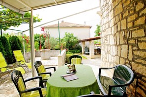 An outdoor patio with a table and chairs, a stone wall, and a building in the background.