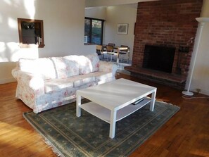Cozy living room with a brick fireplace, white sofa, and patterned rug.