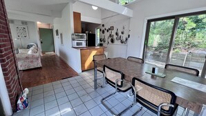 A modern kitchen with a dining area, featuring a large window, a built-in microwave, and a variety of cookware on the wall.