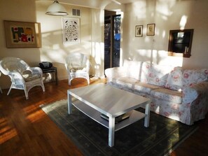 Relax in this stylish living room with a sofa, two chairs, and a coffee table, surrounded by framed pictures and natural light.