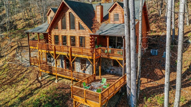 Une grande cabane en rondins dotée de plusieurs terrasses et d’espaces de détente en plein air.