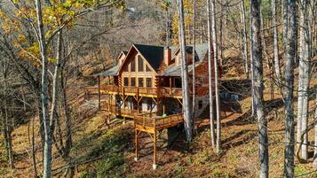 A log cabin with a multi-level deck surrounded by forest.