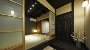 A traditional Japanese room with tatami flooring, a shoji screen door, and a small table with a lamp. - Rinn Tenjincho (Kyoto)