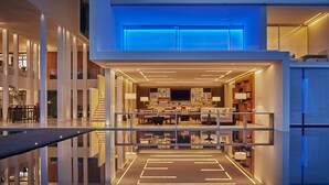 Een modern, meerlaags interieur met een centraal open woonoppervlak, inclusief een keuken en eethoek, omringd door balkons en een reflecterend zwembad.
