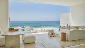 Een moderne woonkamer met een groot raam met uitzicht op een strand en de oceaan.