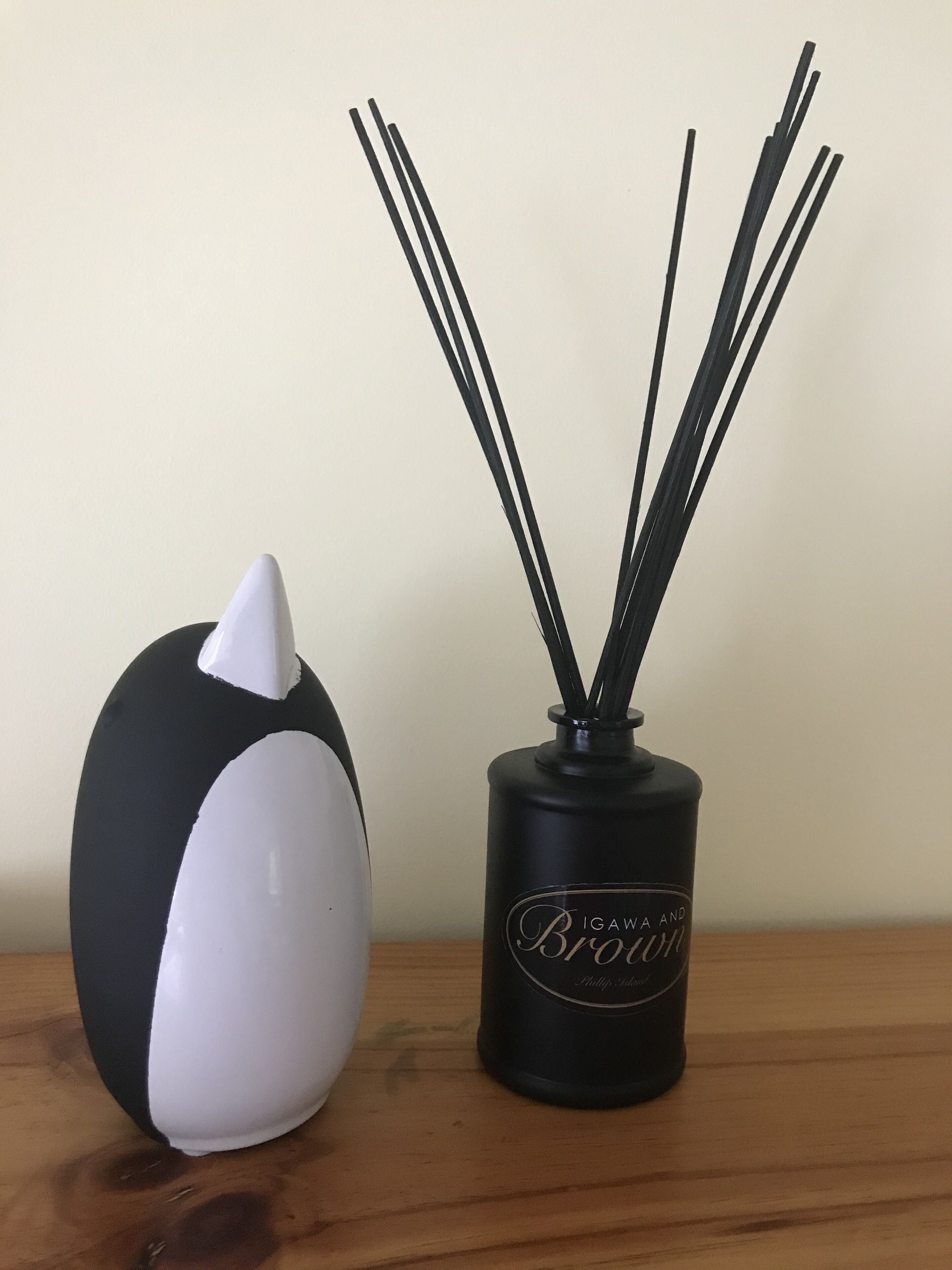 A black and white decorative object and a black vase with reed sticks.