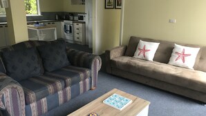 Een woonkamer met een bank, een salontafel en een keuken op de achtergrond.