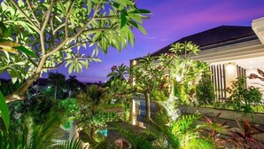 Ein modernes Gebäude mit einem Pool, umgeben von üppiger Vegetation und tropischen Pflanzen.
