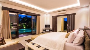 Ein modernes Schlafzimmer mit einem großen Bett, einem Fernseher und einer Schiebetür zum Pool.