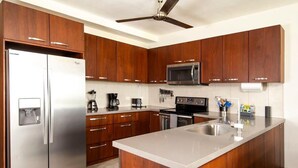 A modern kitchen with wooden cabinets, stainless steel appliances, and a central island. - Newly Remodeled Beachfront Condo, Ground-Floor Terrace & Direct Access to Playa Flamingo (Santa Cruz, Guanacaste, Playa Flamingo)