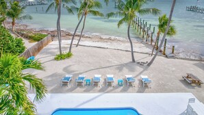 Un espace piscine situé au bord de la plage, avec des chaises longues et une vue sur l’océan.
