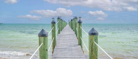 A wooden pier extending into the ocean with railings on both sides.