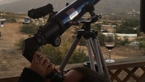 A telescope on a tripod with a person adjusting it. - Labios Tintos Bungalow, Valle de Guadalupe, BC, México (Las Lomas)